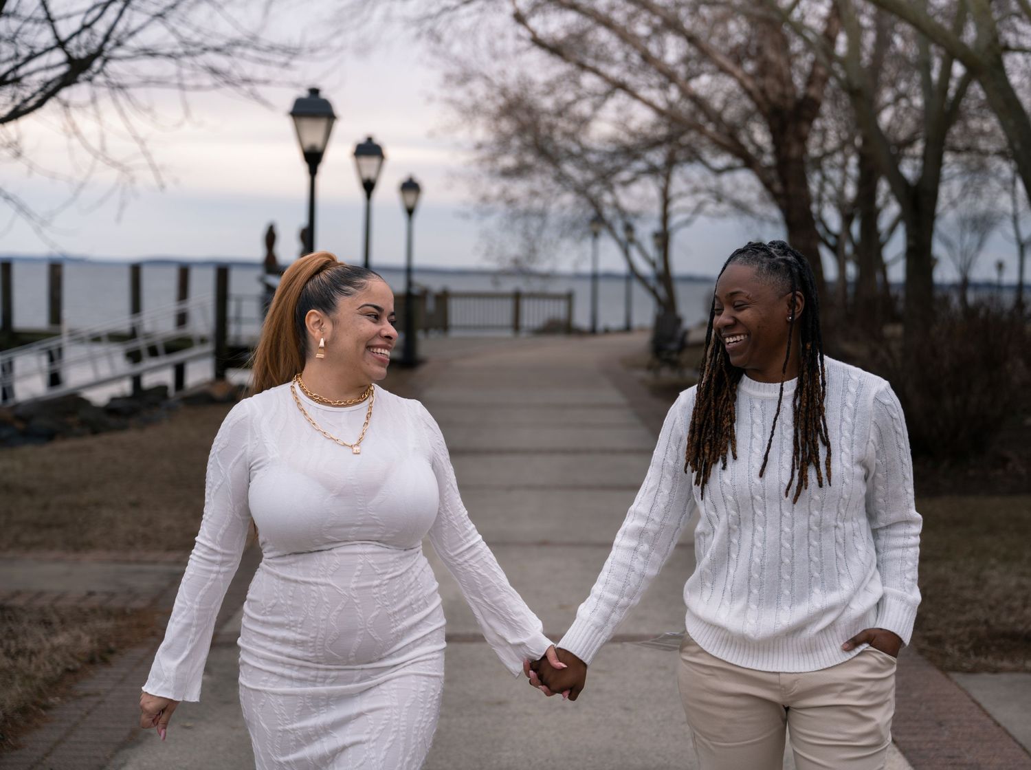 People walking together on a boardwalk at sunset wearing white and cream colored outfits.