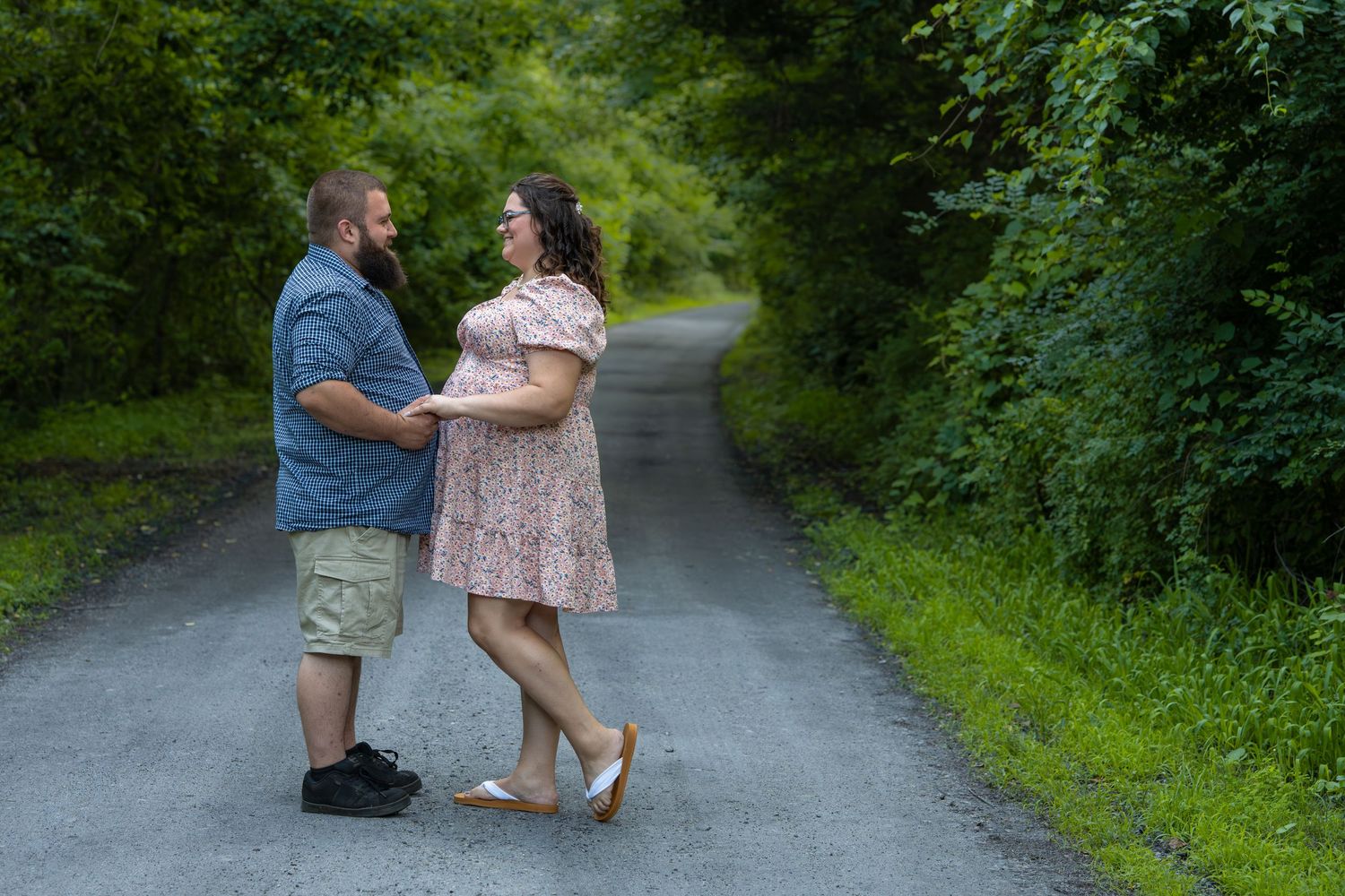A romantic proposal moment captured on a tree-lined path in a park.