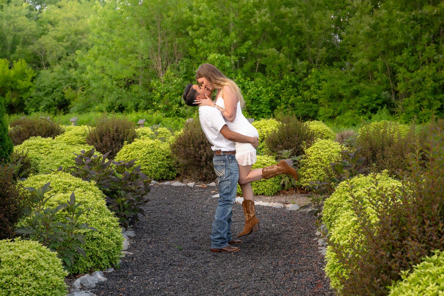 A romantic photoshoot in a landscaped garden with mulch paths and evergreen shrubs.