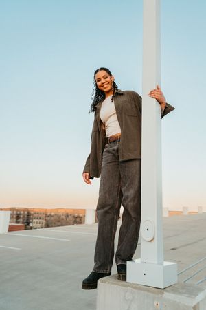 A series of fashion photos showing someone in a brown blazer and wide-leg pants posing against a rooftop setting at sunset.