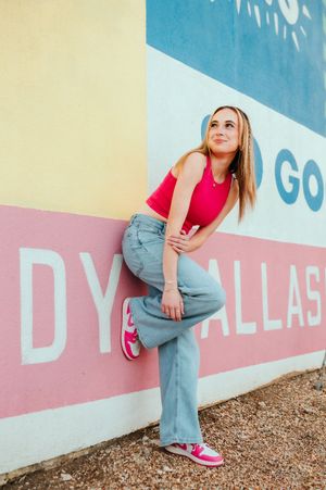 A person in jeans and pink shoes poses against a colorful geometric wall mural in three dynamic poses.