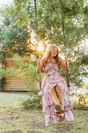 A person in a flowy pink dress dances joyfully in a golden field at sunset.
