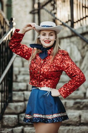 A stylish western outfit featuring a red sequined jacket and blue skater skirt with a gray cowboy hat for a retro look.