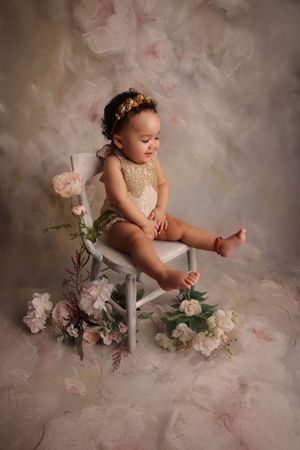 Toddler sitting on chair smiling holding flowers