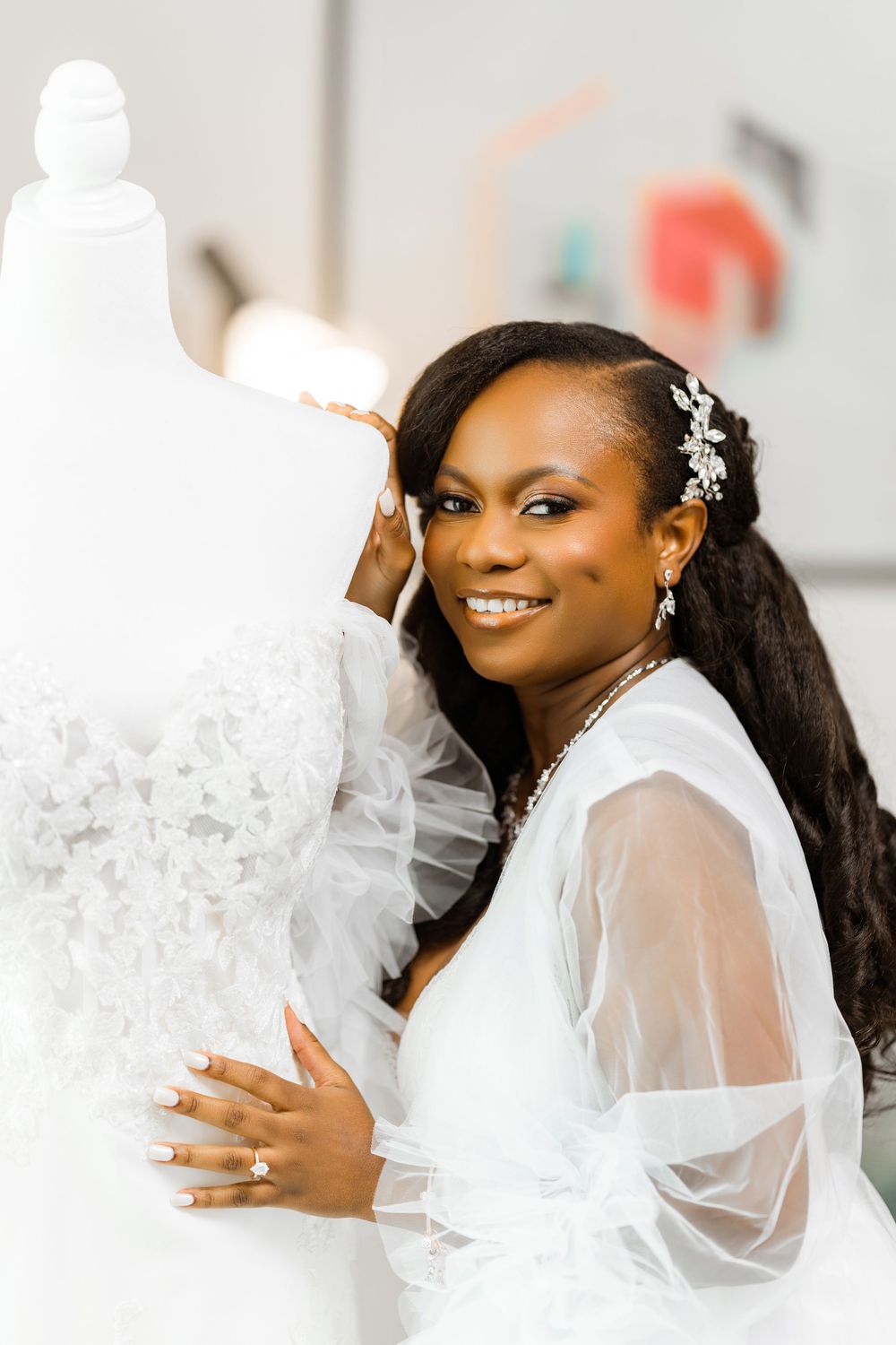 Beautiful bride in a sheer white robe smiles radiantly while adorned with floral hair accessories and elegant earrings.