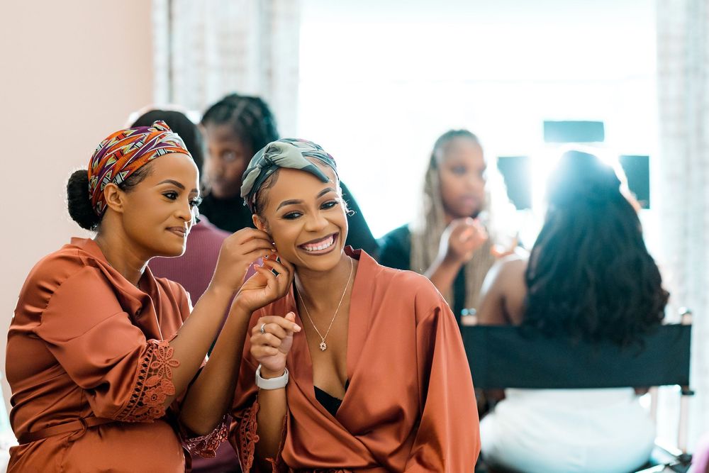 People enjoy a lighthearted moment together while wearing silk robes in what appears to be a getting ready setting.