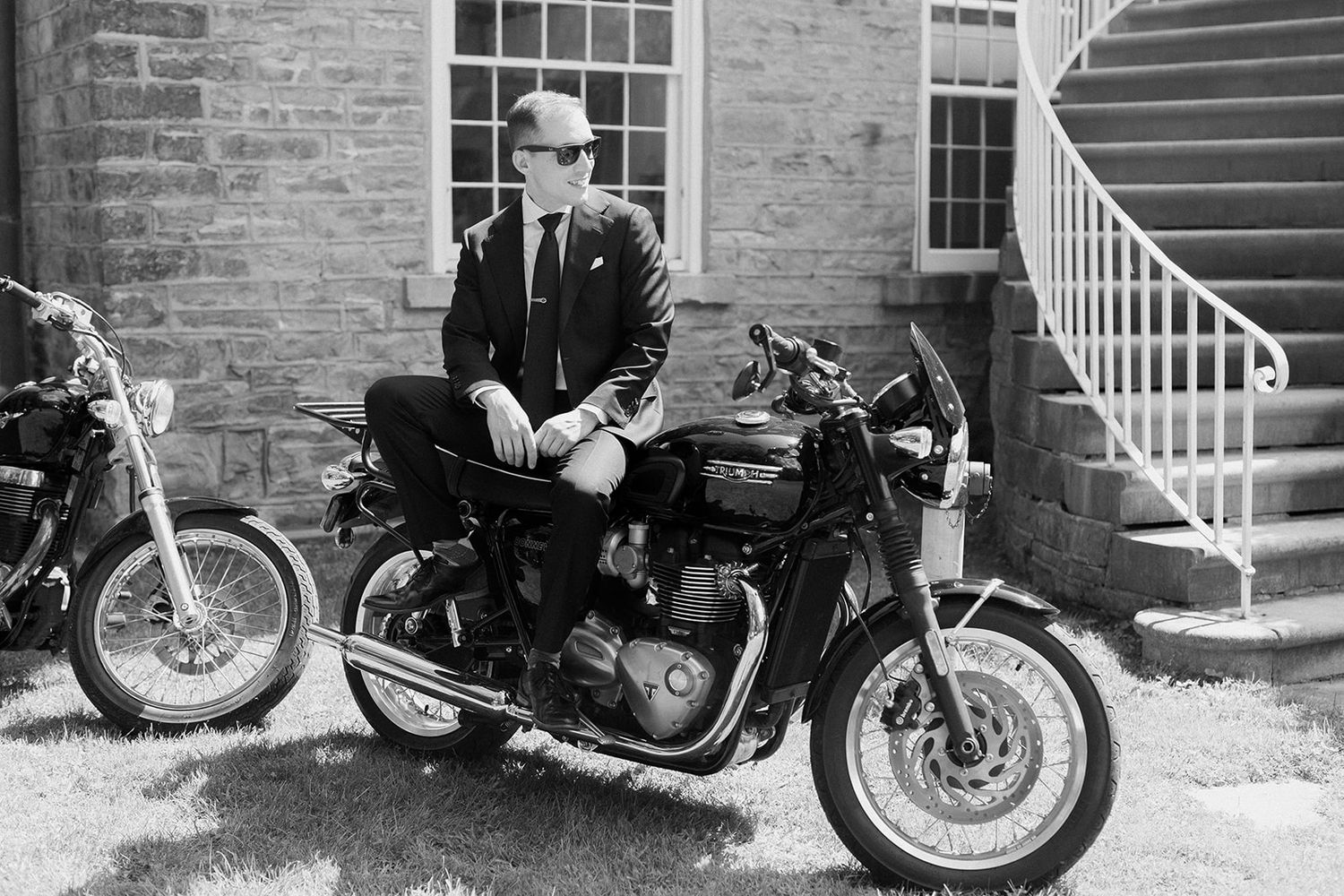 Vintage motorcycles lined up against a brick building with white stairs.