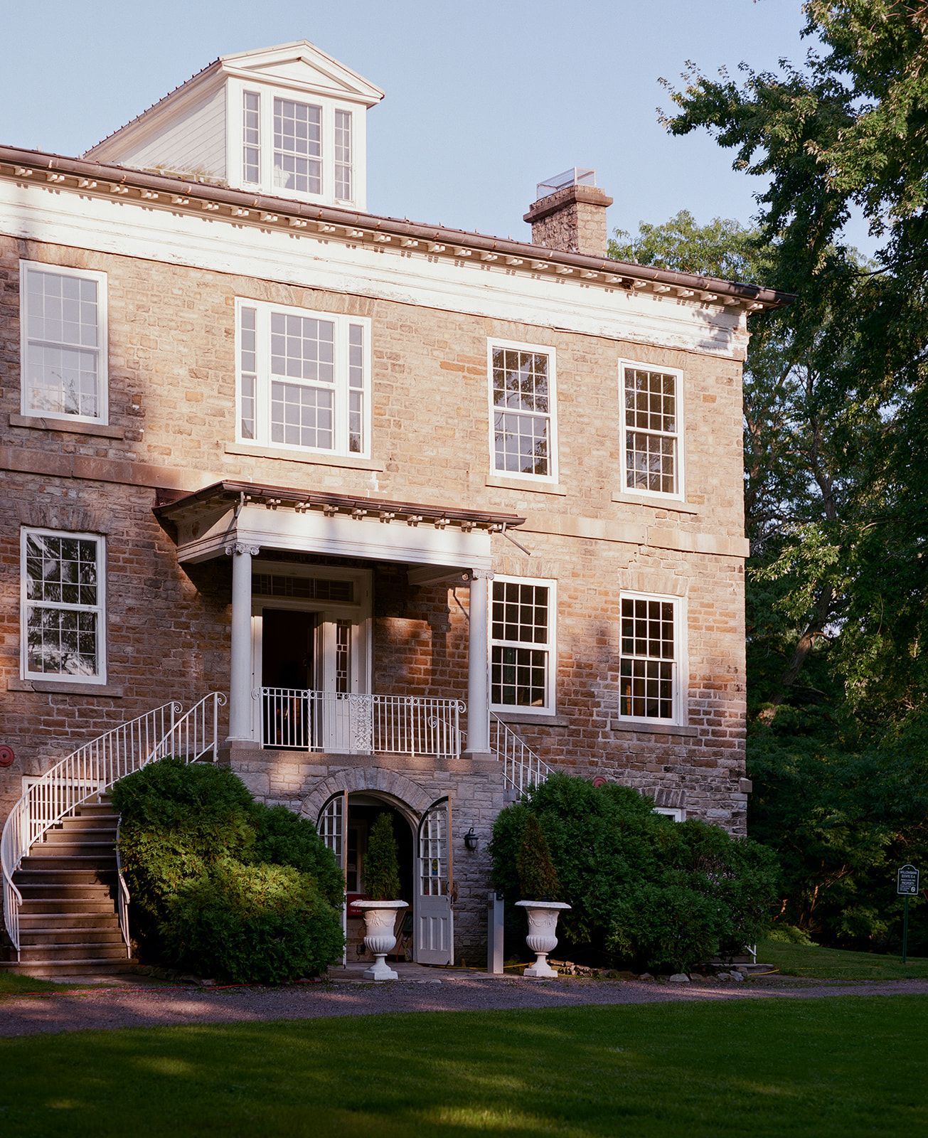 Historic stone mansion with white trim and multiple windows photographed during daytime.