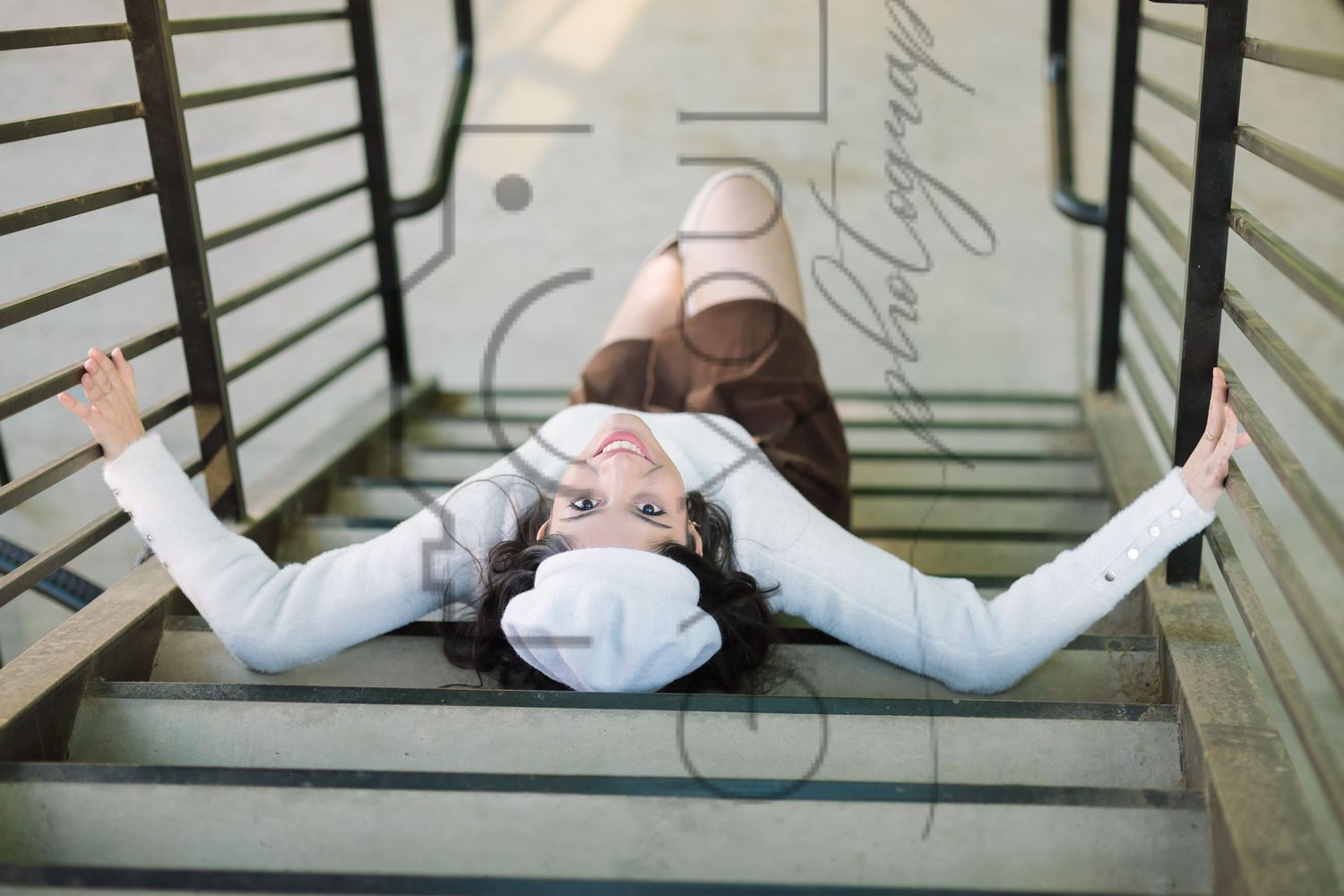 A person in a white protective face mask lies on wooden stairs with arms outstretched.