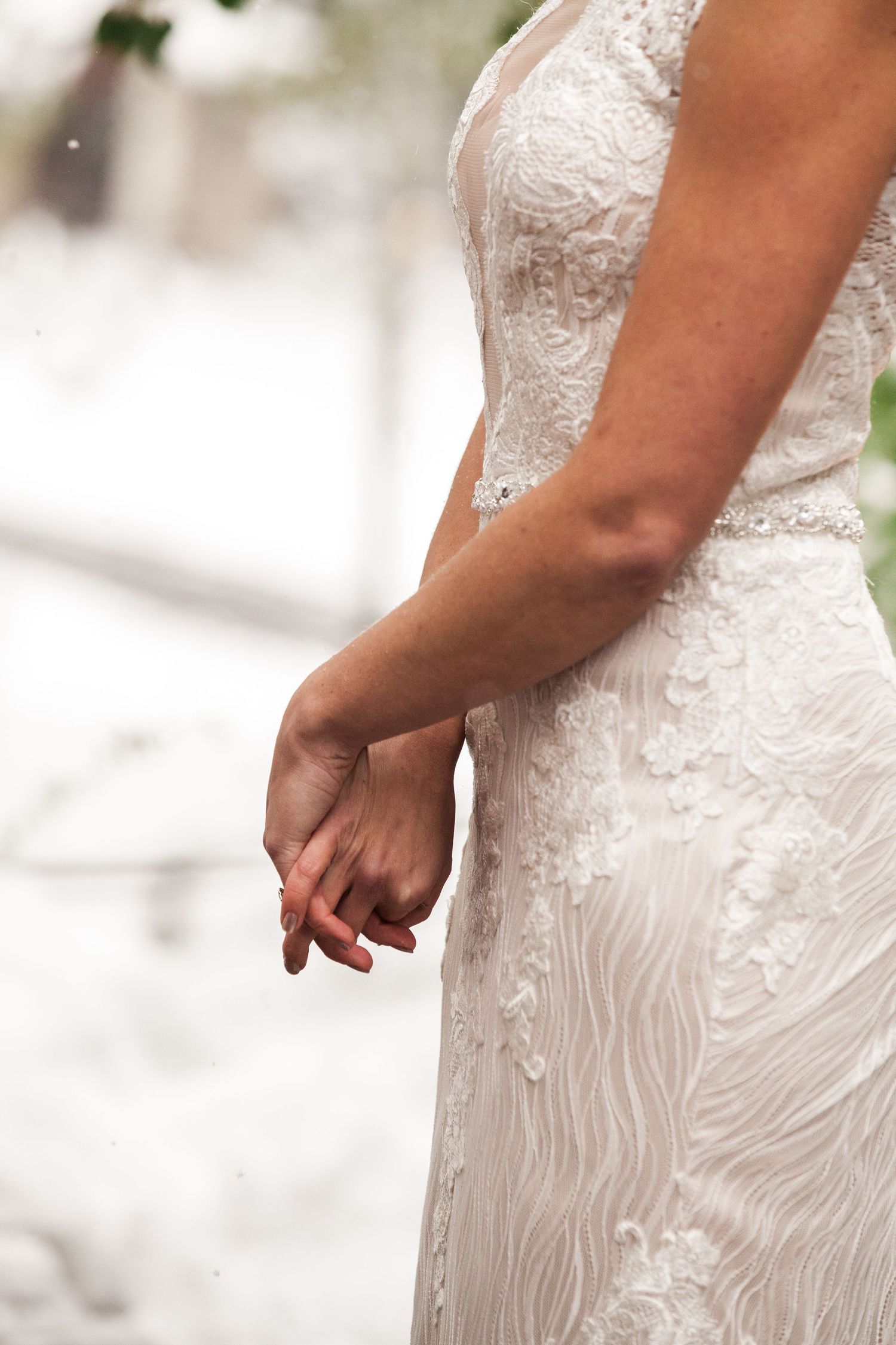 Close-up detail of a white lace wedding dress showing intricate pattern and fitted silhouette.