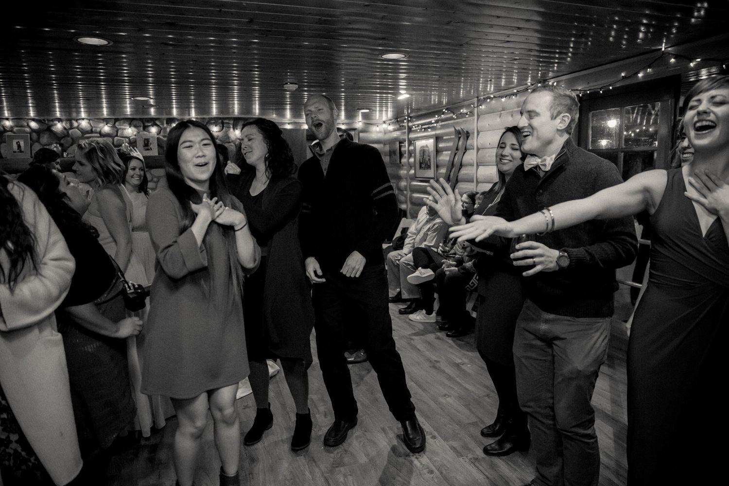 A lively black and white photo of people dancing and socializing during an evening event at an indoor venue.