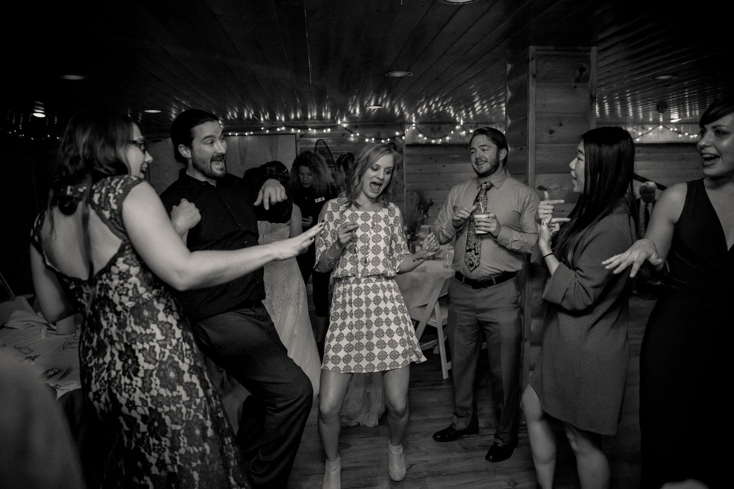 Black and white photo of people dancing and socializing at a vintage-style party in a bar setting.