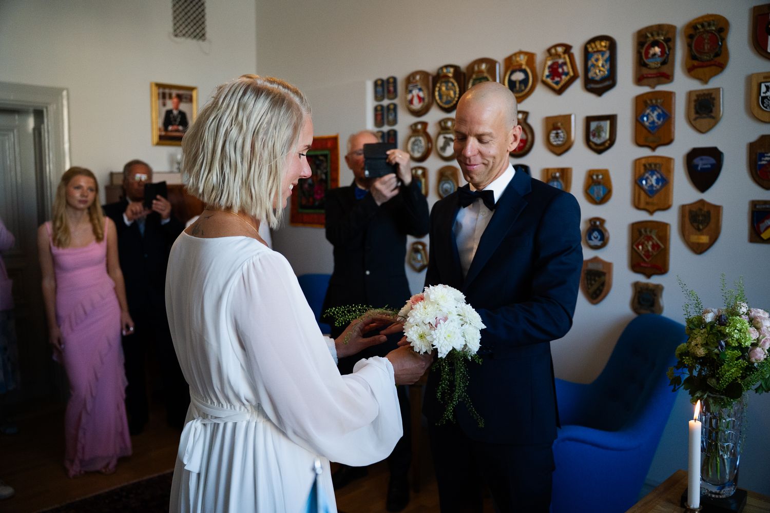 A couple exchange vows during an intimate ceremony with decorative wooden plaques adorning the walls behind them.