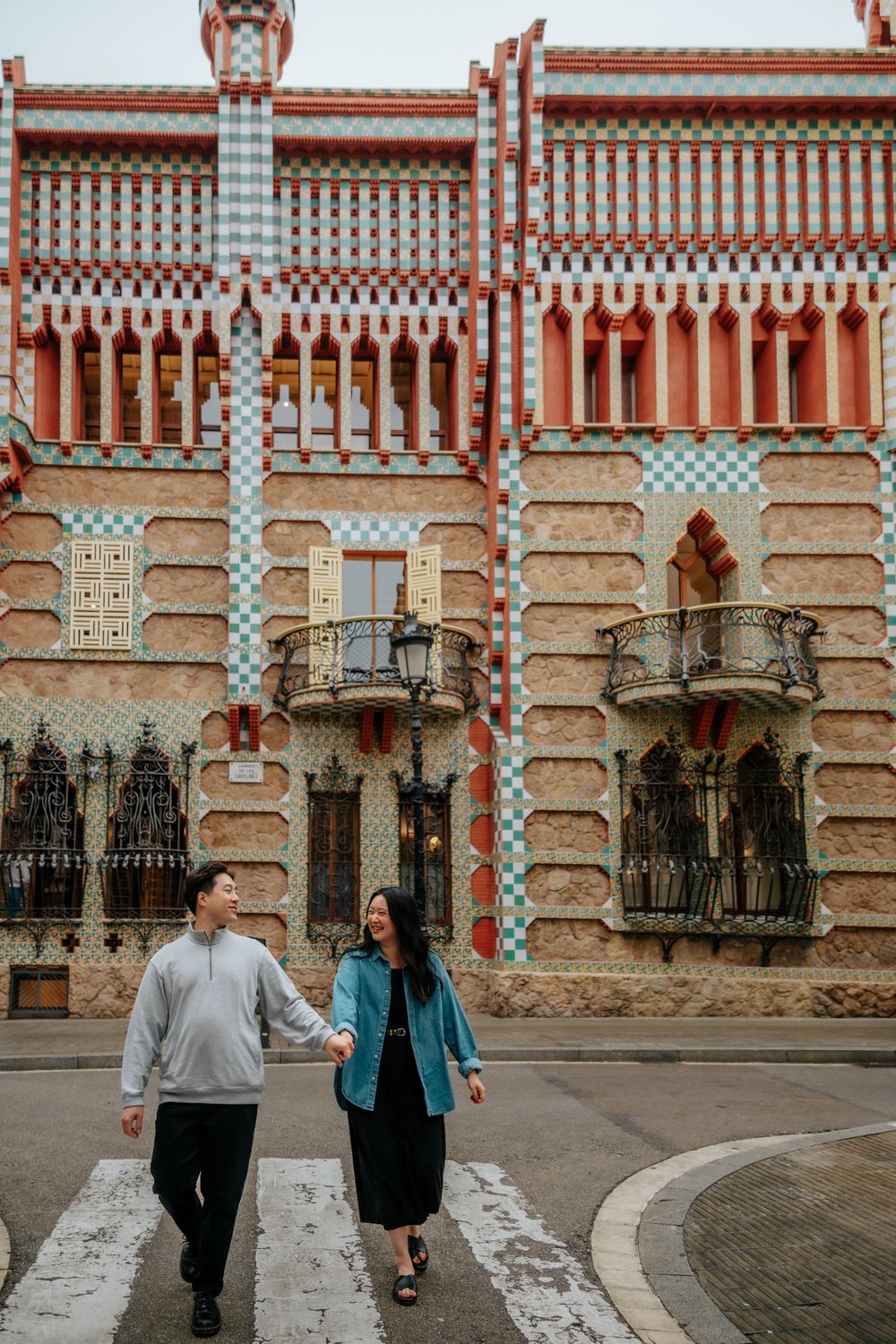 Cozy couple moment on a rainy morning beside Gaudí’s mosaic wall.