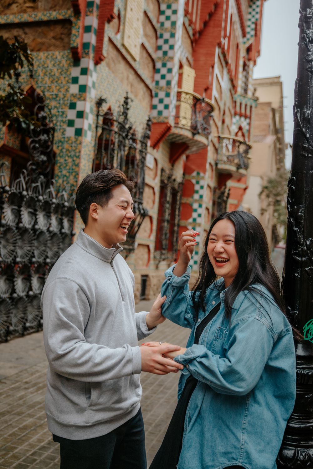 The couple walking hand-in-hand with umbrellas along Casa Vicens’ tiled walkway