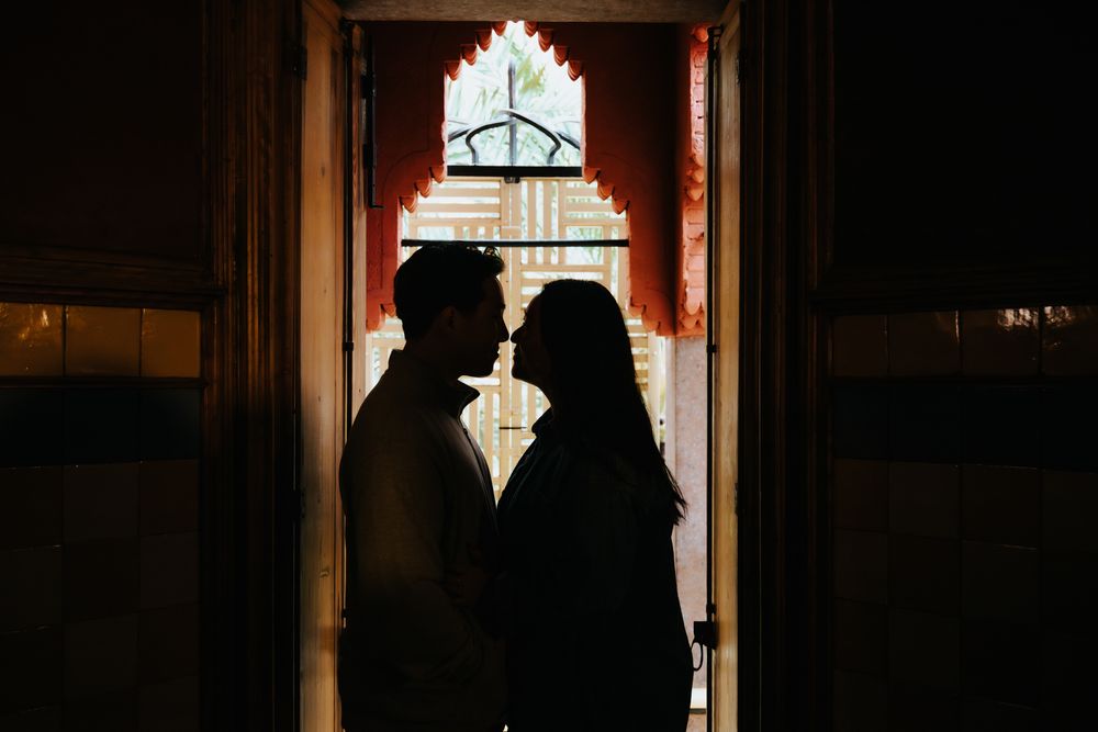 Couple framed beneath a Casa Vicens arch with reflections on the wet ground.