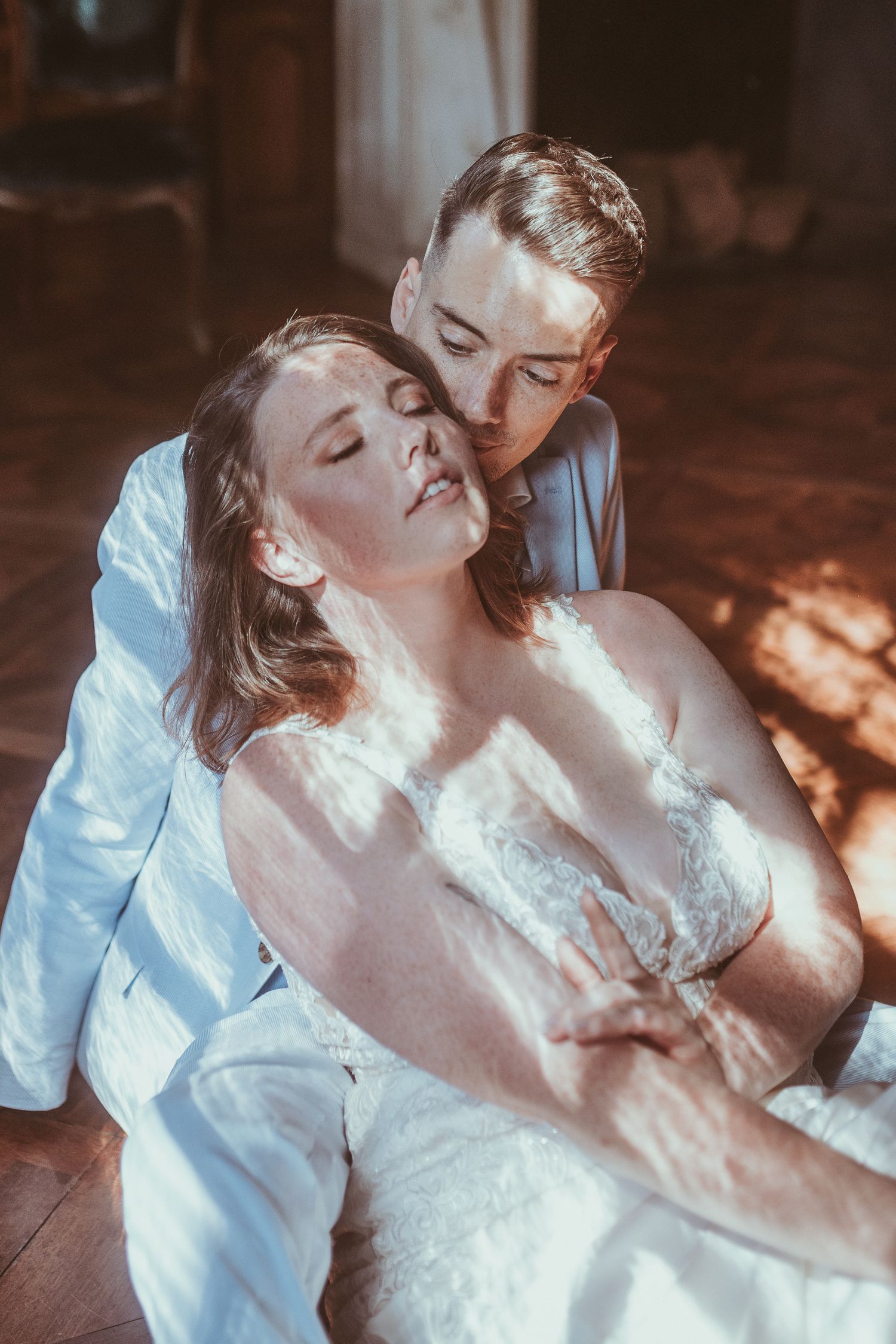 A romantic couple in wedding attire share an intimate moment in dramatic lighting.