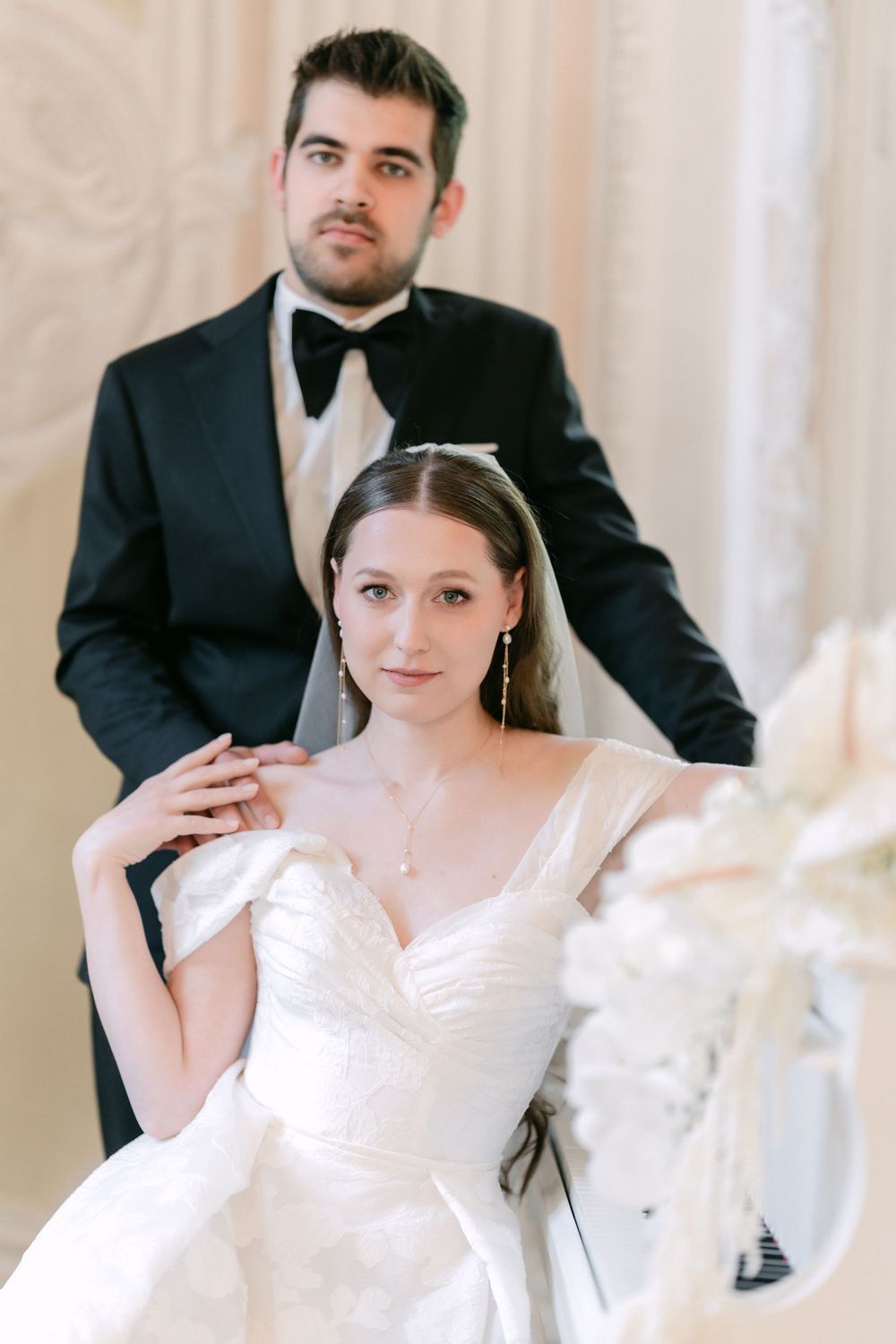 An elegant wedding photo showing a couple in formal attire, with the bride in a white dress and groom in classic tuxedo.