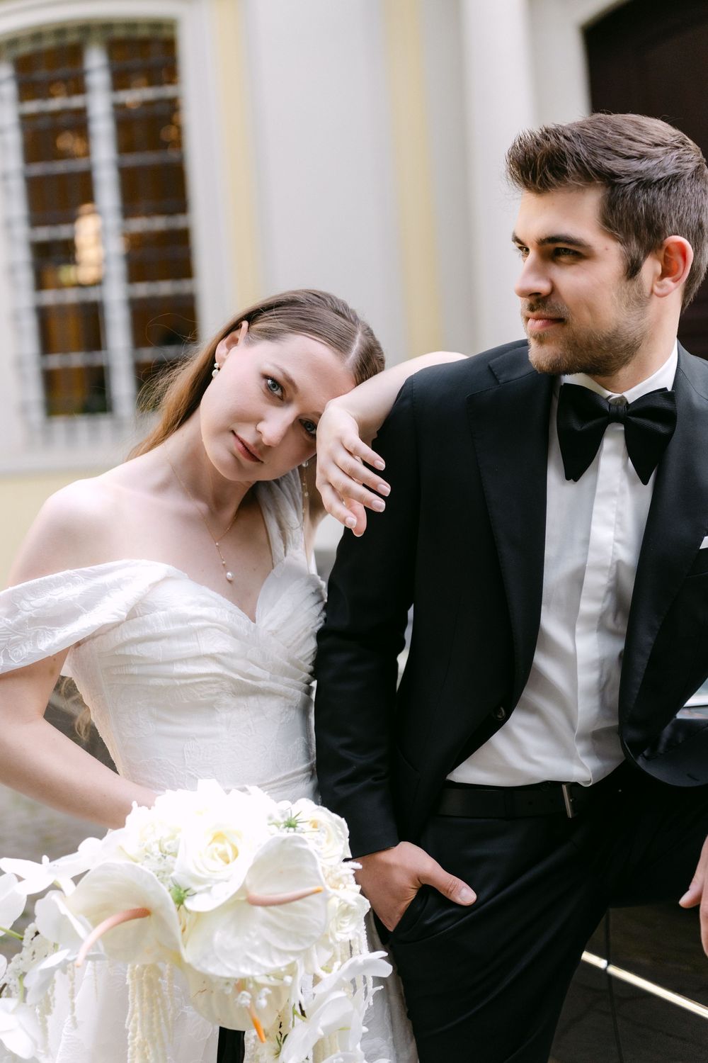 A romantic wedding moment with a couple in formal attire including a white wedding dress and black tuxedo with bow tie.