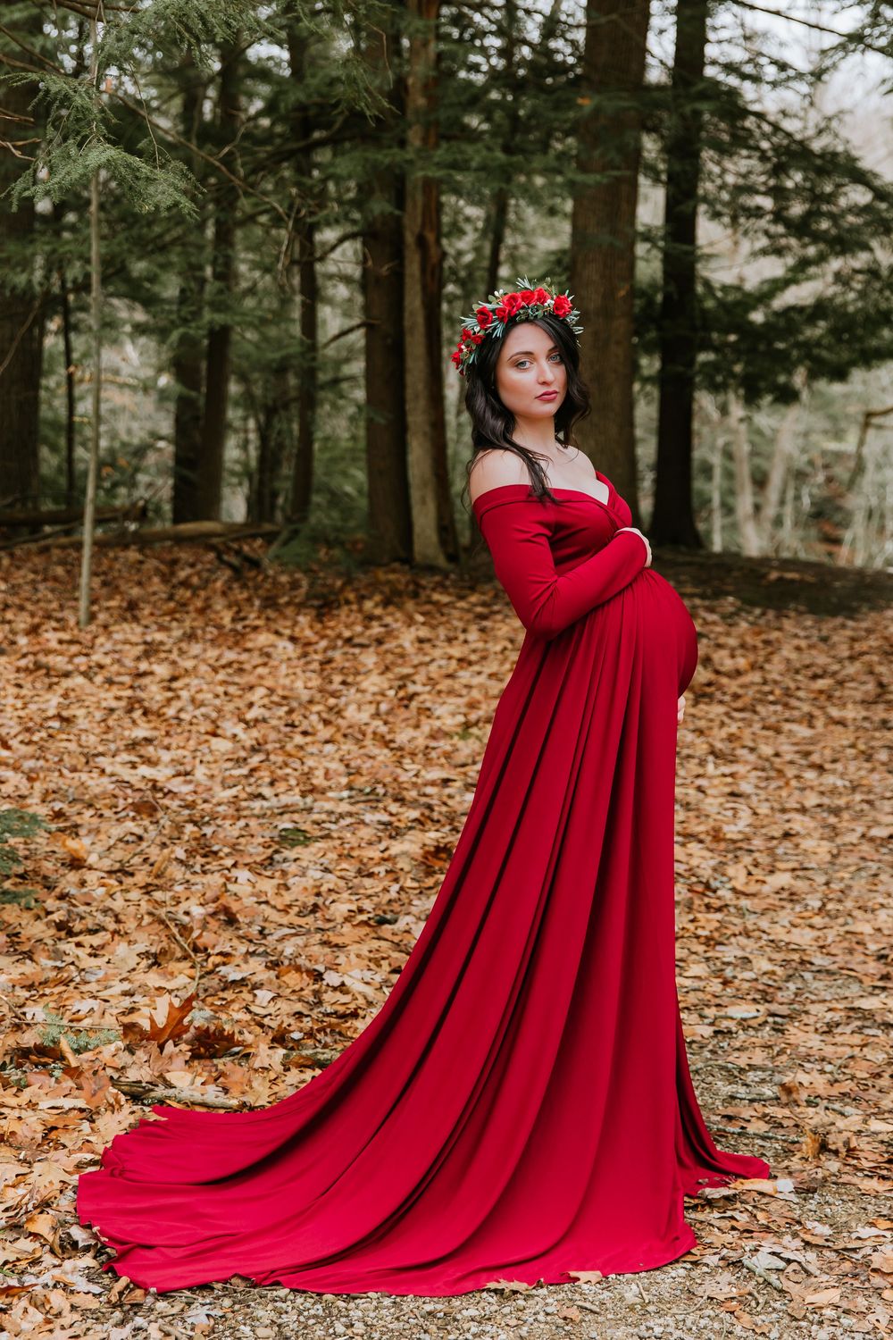Flowing red dress with long train photographed in autumn forest setting.