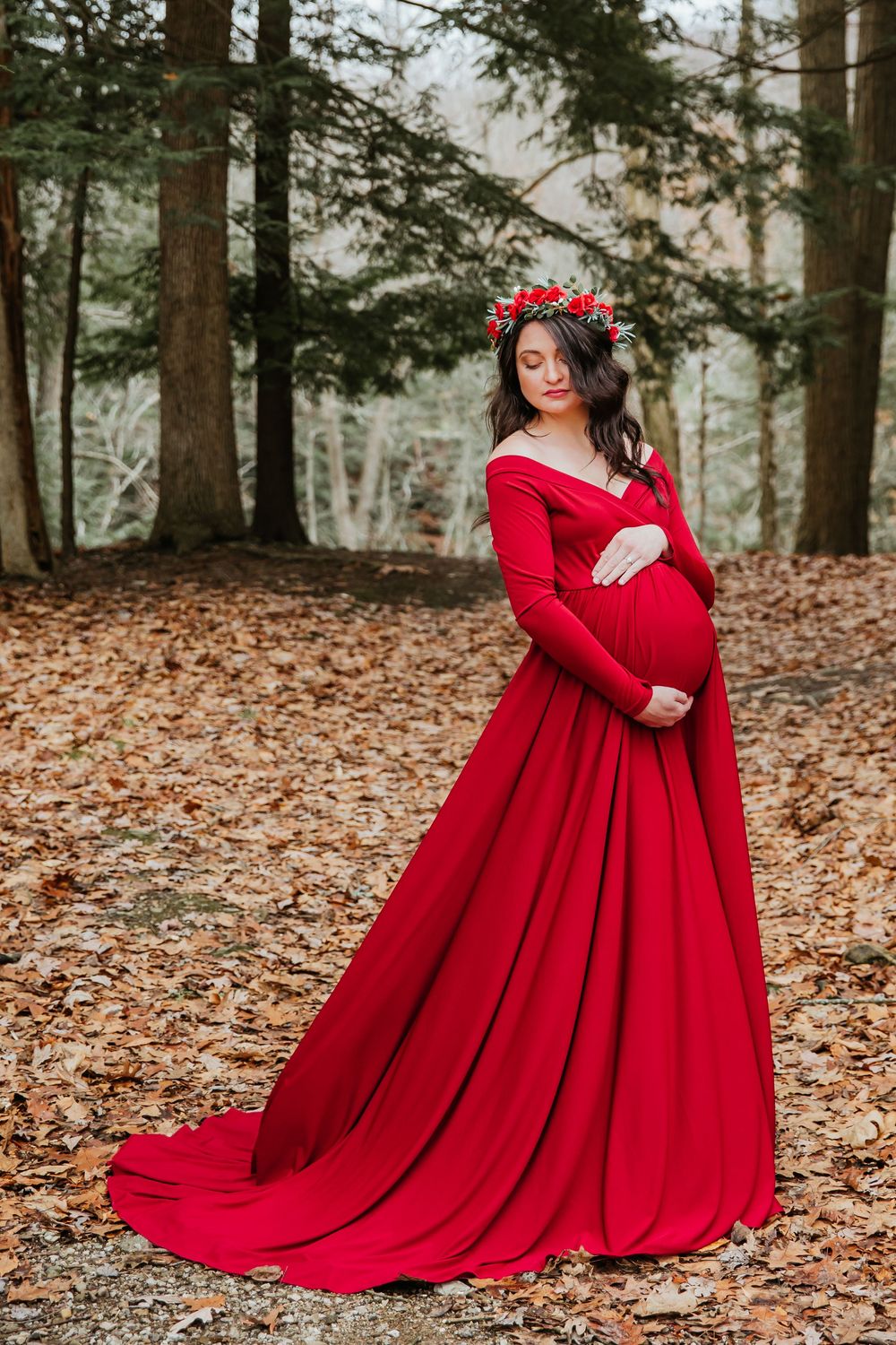 Dramatic full-length maternity photo with red dress train in autumn forest setting.