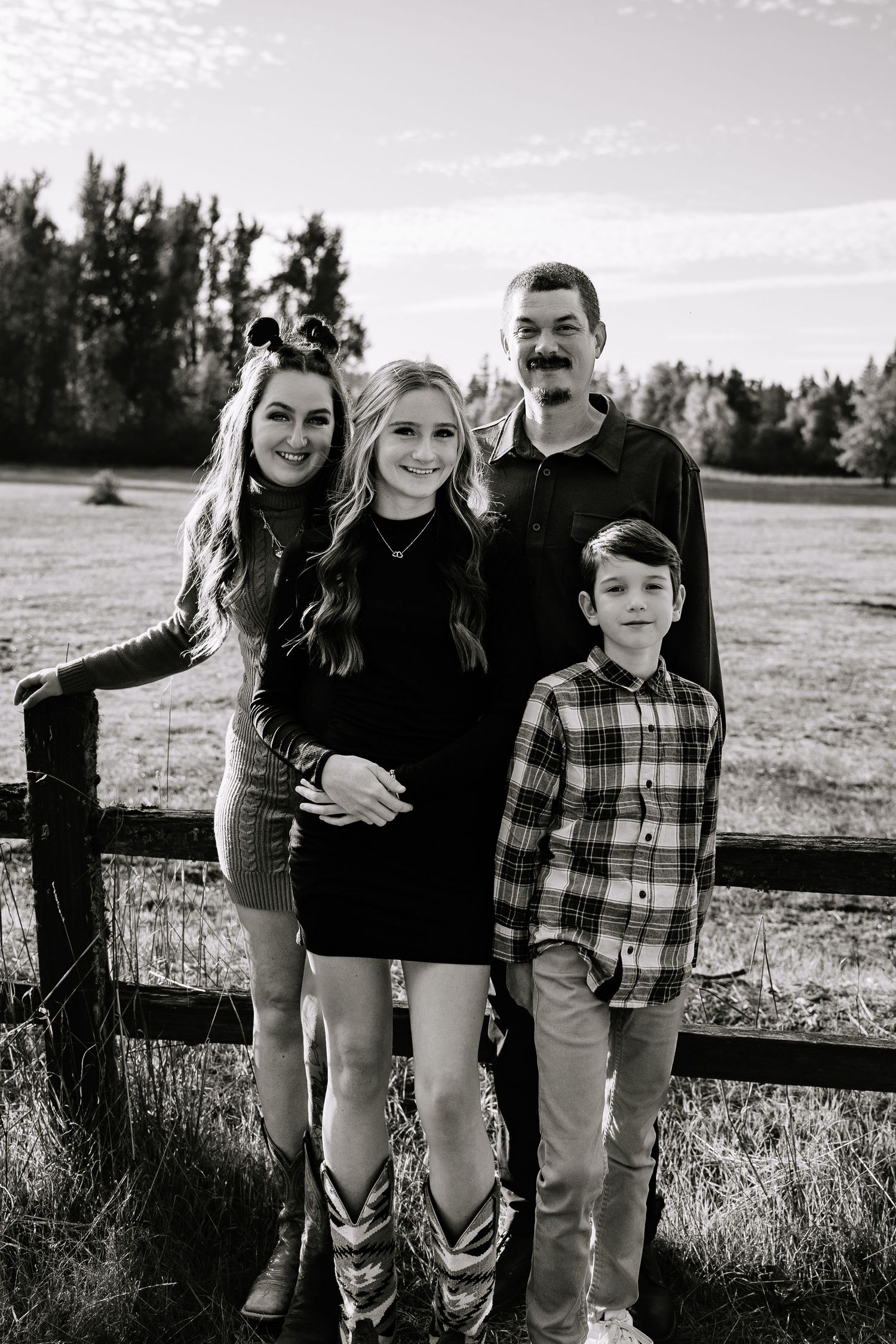 A candid family photo session in a grassy field at sunset with casual outfits and natural poses.