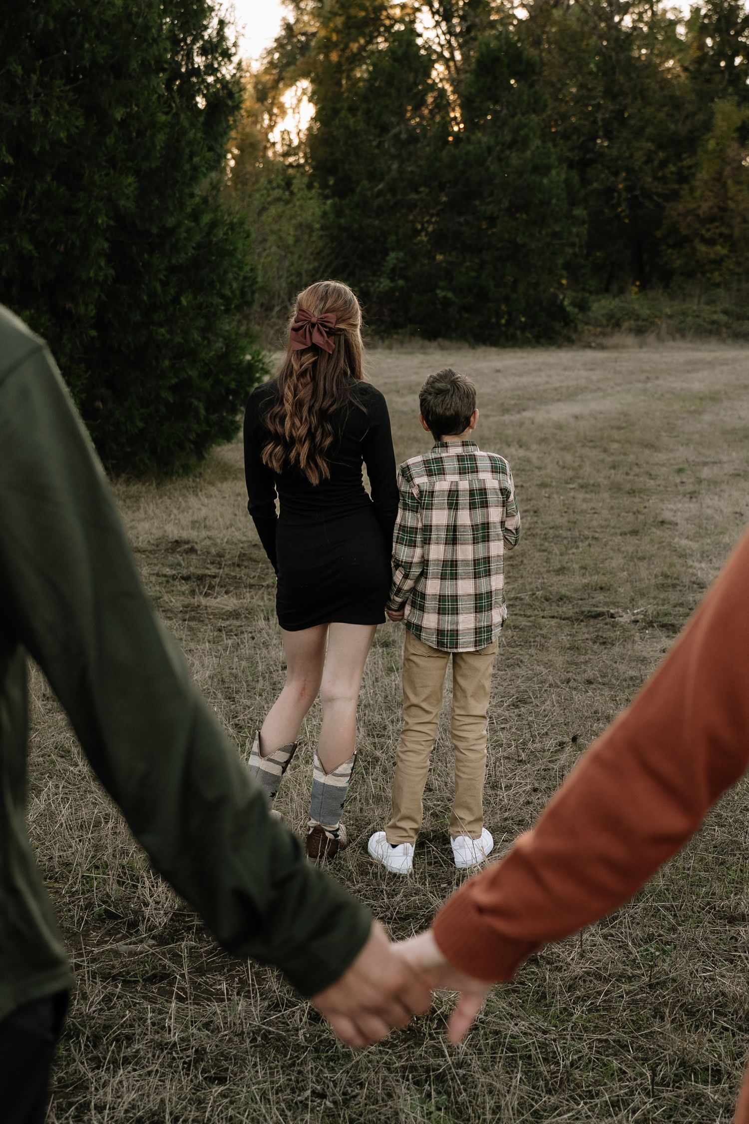 Family members walking together hand in hand through a grassy field at sunset.