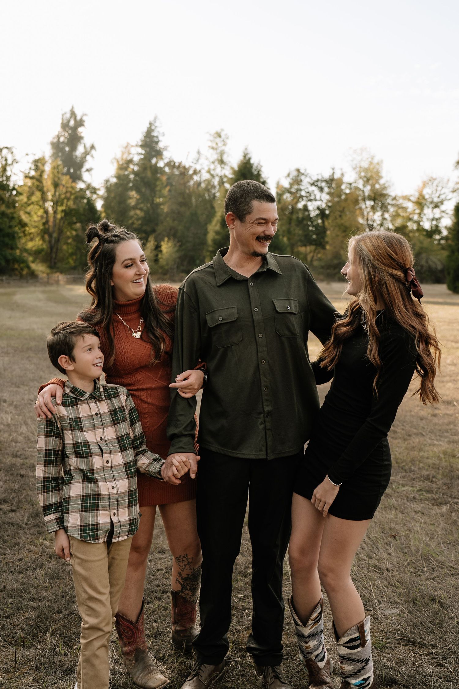 Family members laughing and embracing together during an outdoor photoshoot in golden hour lighting.