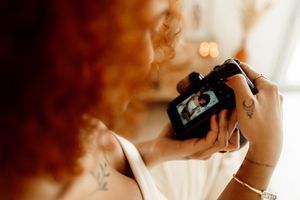 Close-up view of hands holding a digital camera with soft window light in background.