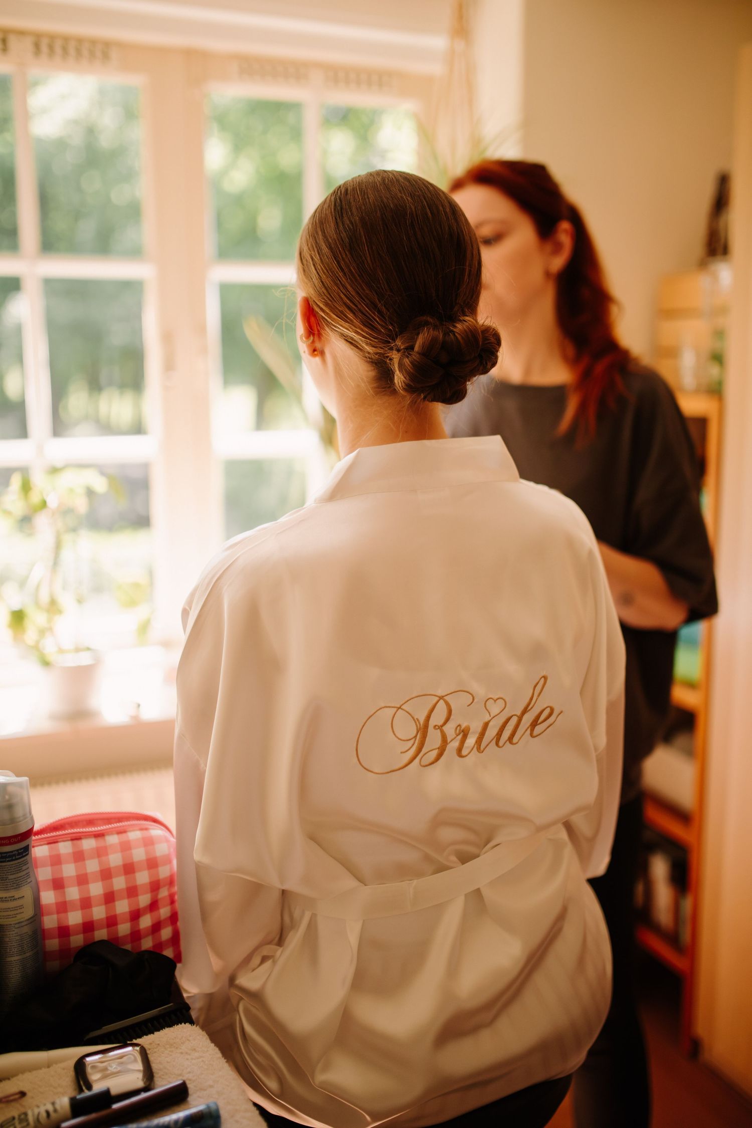 A white satin robe with 'Bride' embroidered on the back during wedding preparations.