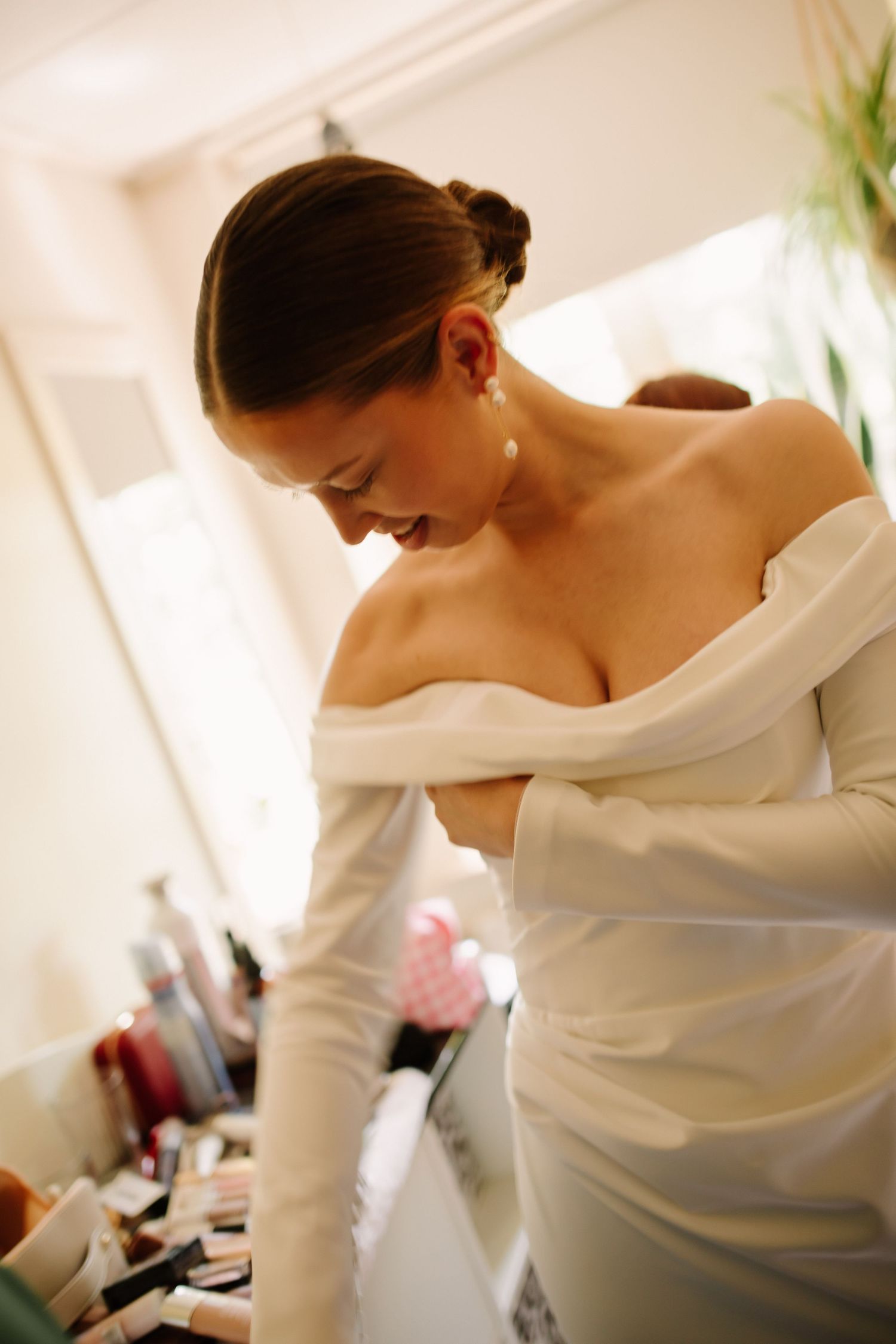 A close-up shot of someone in an elegant white wedding dress during preparation.