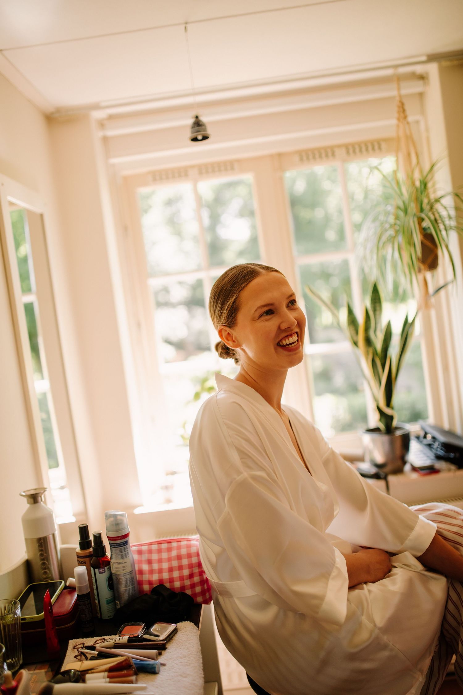 A person in a white robe sitting at a table with a red checkered cloth during wedding preparations.