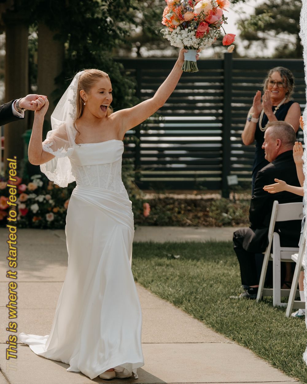 Wedding party walking joyfully outdoors along a garden pathway with white dresses and flowing bouquets.