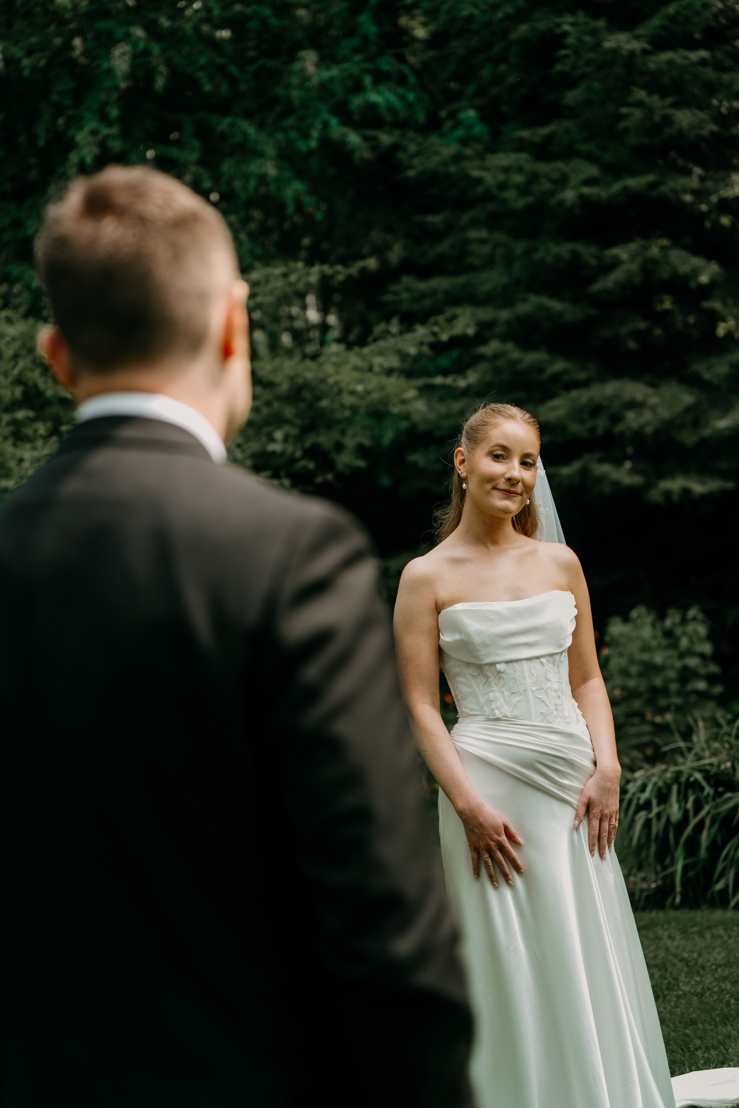 A couple shares a moment in a garden setting during their wedding, with the bride wearing an elegant white gown.