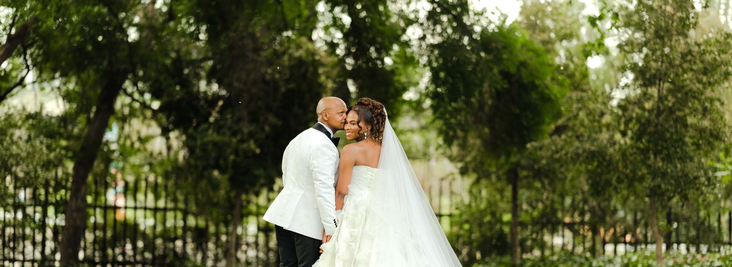 Wedding couple poses in front of a modern white architectural building with multiple horizontal windows.