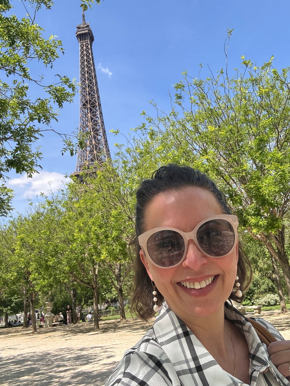 A series of sunny selfie photos taken near the Eiffel Tower in Paris with trees and blue sky in the background.