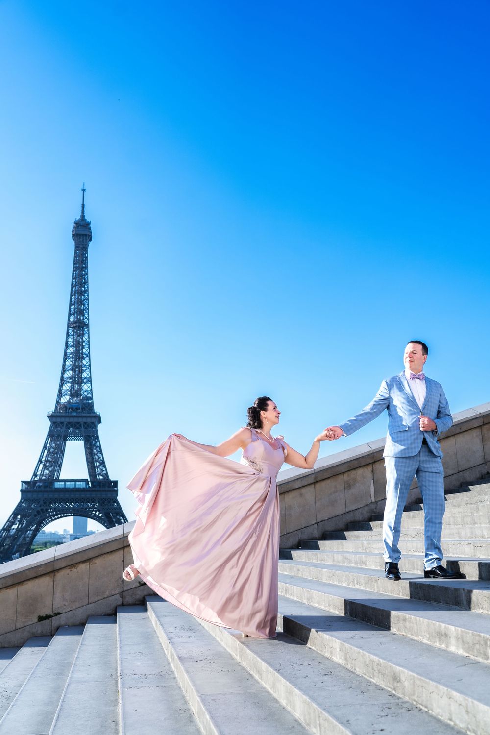 A romantic couple poses on the Trocadero steps with the Eiffel Tower in the background in Paris, France.
