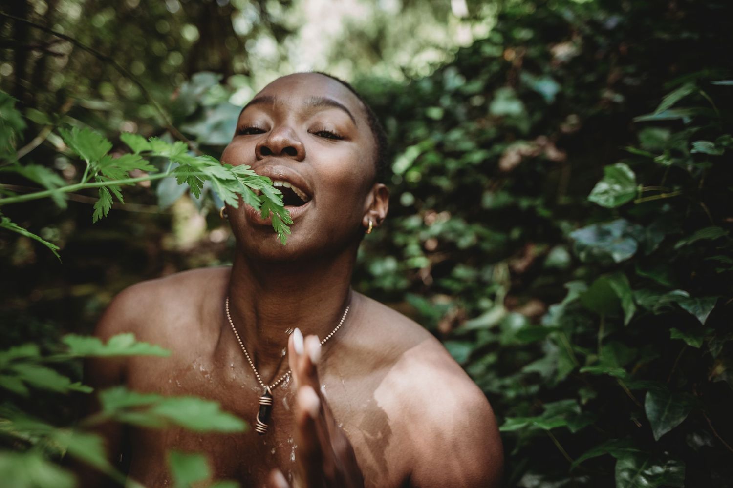 mulher negra na natureza em foto colorida com a boca aberta em forma de gratidão  em uma sessão fotográfica feminina na natureza em Portugal