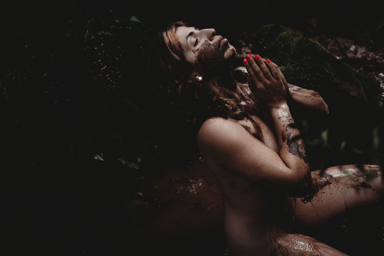 Mulher agradece  em ritual da lama em uma foto colorida  com luz central ,  numa sessão feminina de rituais em Portugal.