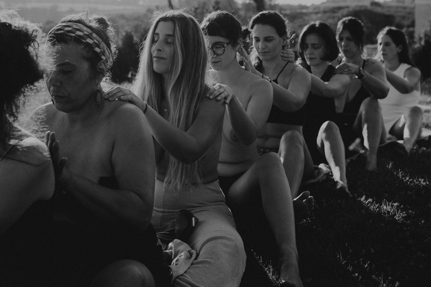 Mulheres agradecem  em ritual da lama em uma foto preto e branco com luz central ,  numa sessão feminina de rituais em Portugal.