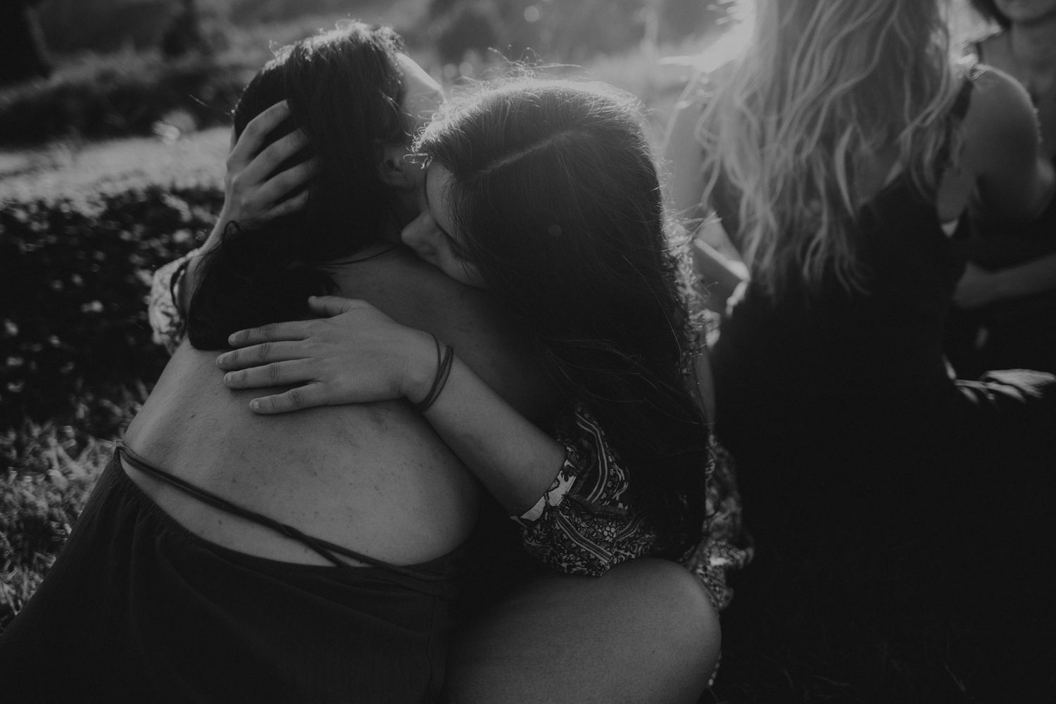 Foto em preto e branco onde duas mulheres se abraçam em um circulo feminino em momento intimo em um ritual em Portugal