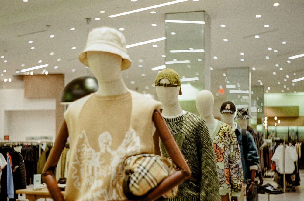 Modern clothing retail store interior with white mannequins displaying fashion merchandise under bright lighting.