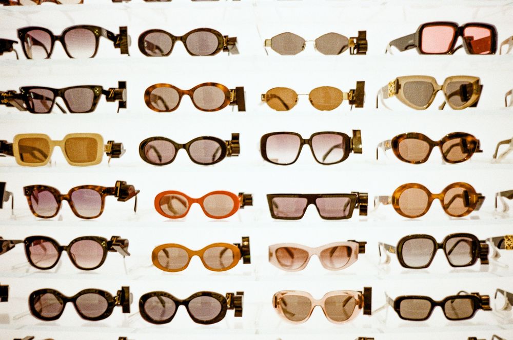 A collection of vintage sunglasses and eyewear frames displayed in organized rows against a white background.