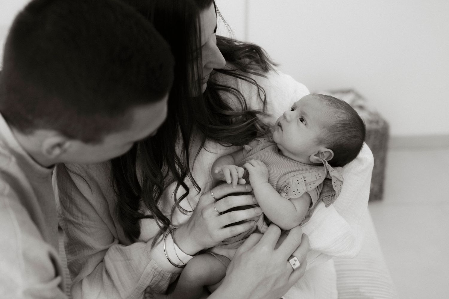 A parent tenderly holds and gazes at their newborn baby in an intimate black and white photograph.