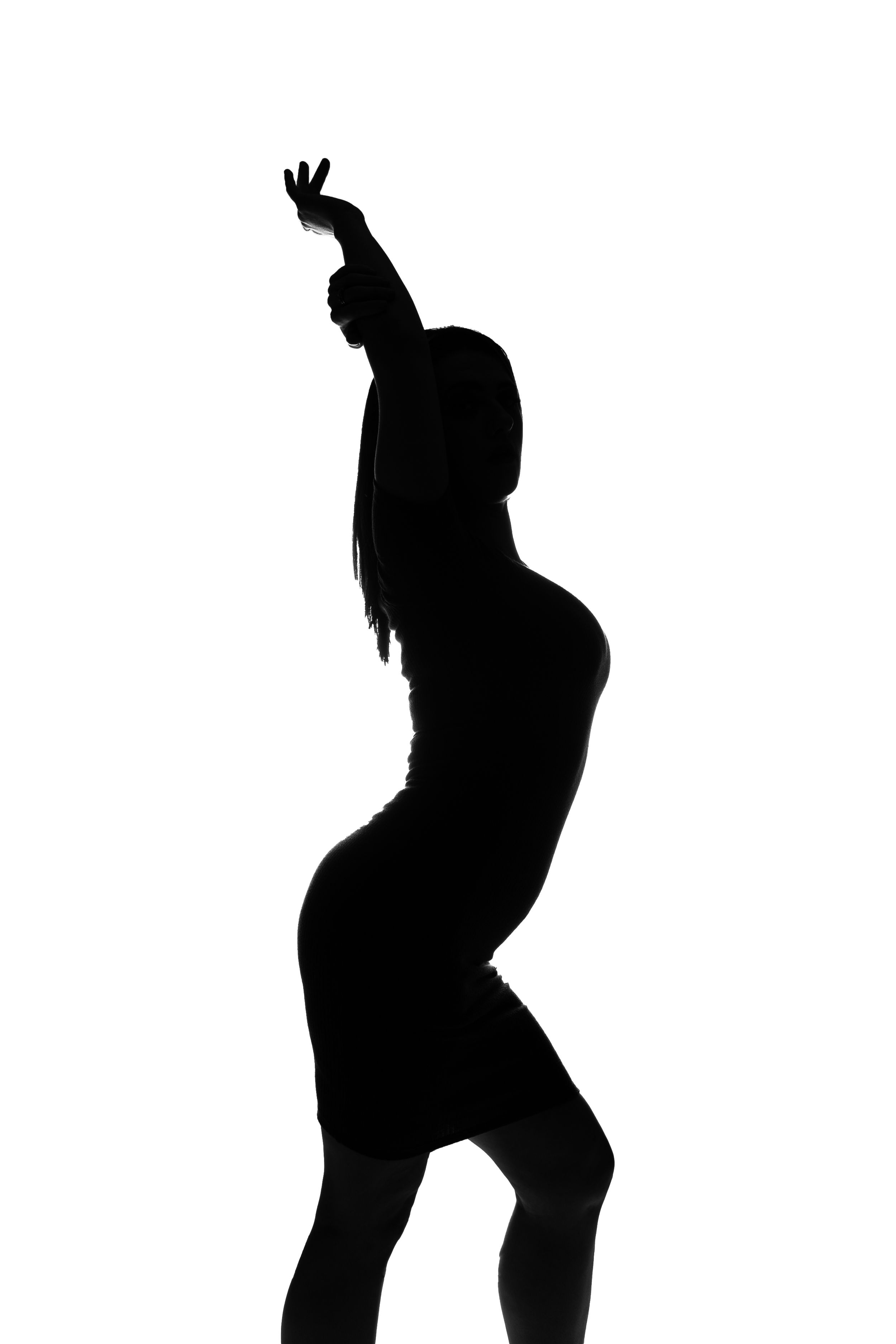 Silhouette of a dancing figure in a form-fitting dress with one arm raised against white background.