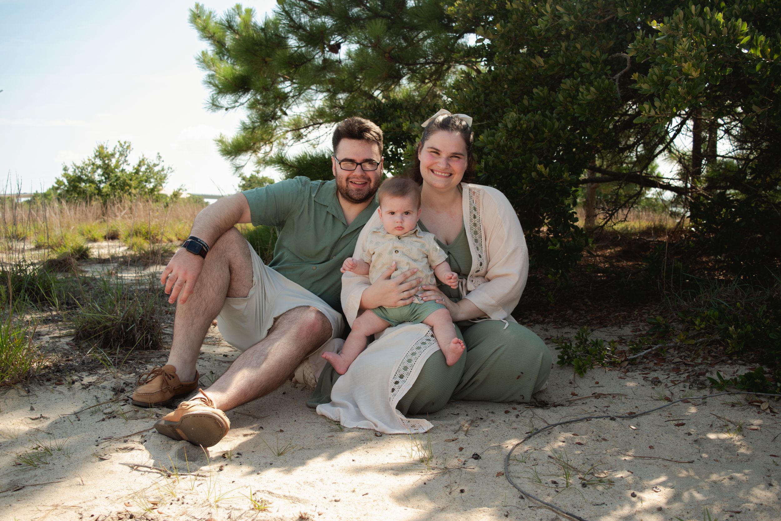Two people relax together on a sandy beach shoreline during a sunny afternoon outing.