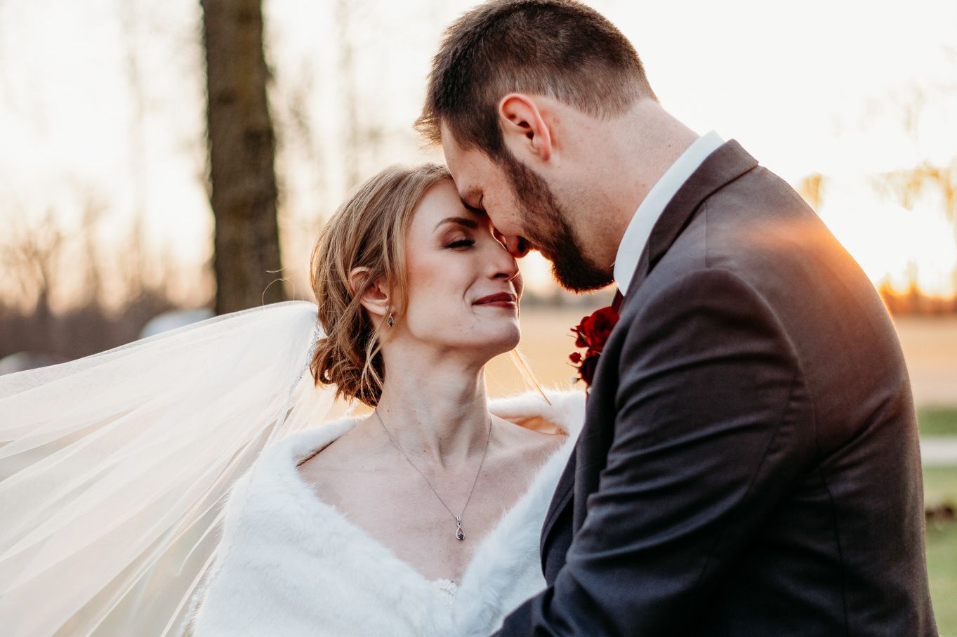 A bride and groom stand in front of a glowing sunset in St. Louis Missouri after their Catholic wedding ceremony.