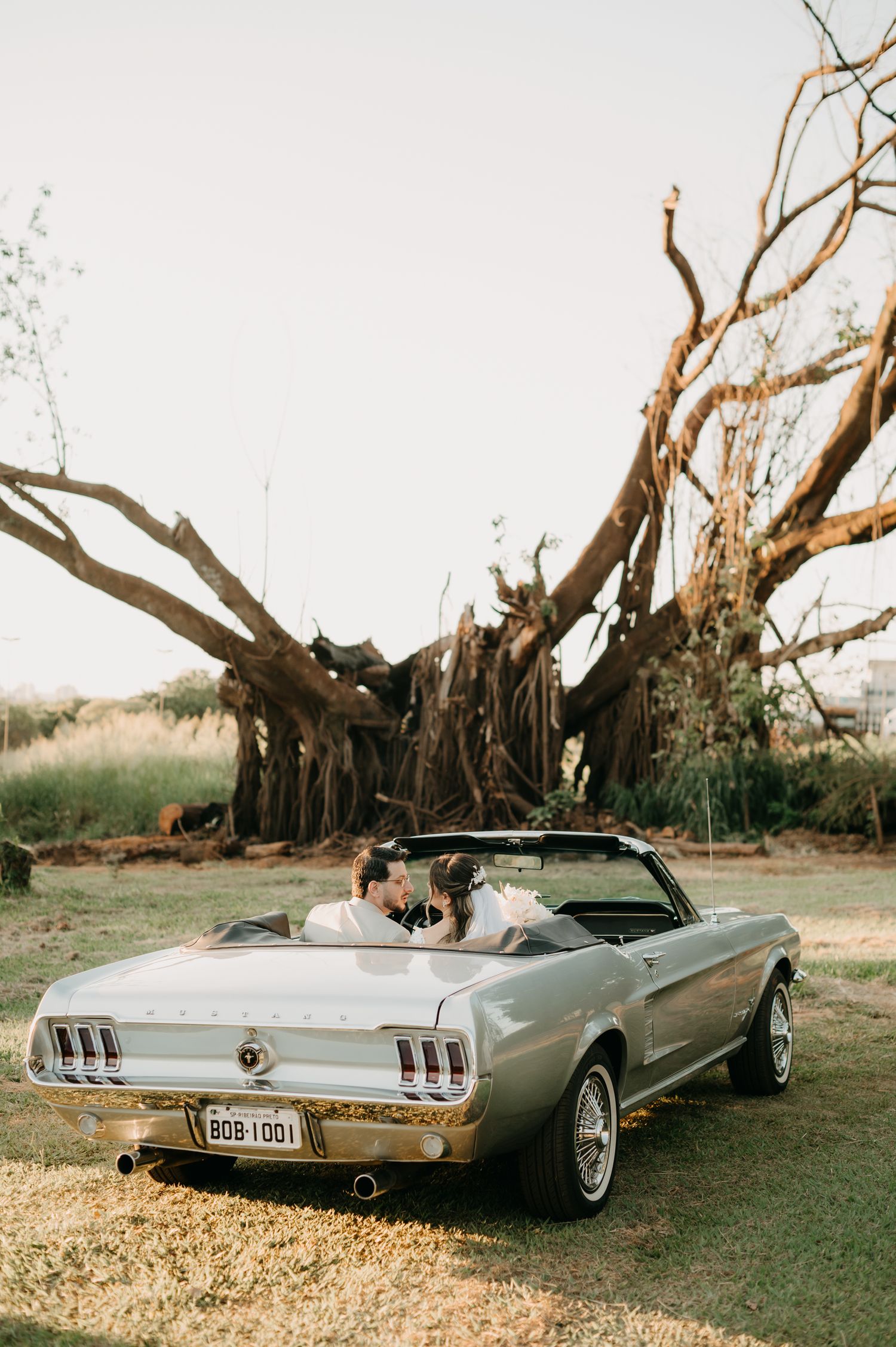 Casal sentado no carro com vista para um arvore olhando um para o outro com Ever Two Fotografia