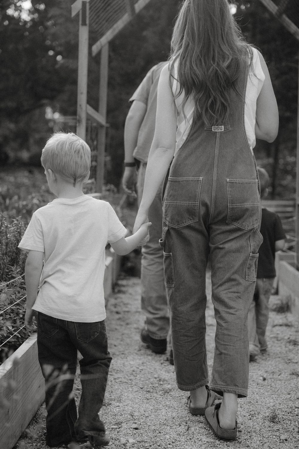 A tender black and white photo shows a parent and child walking hand in hand down a garden path.