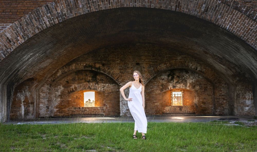 Historical brick archway illuminated by glowing wall sconces in Fort Pulaski creating a dramatic tunnel effect.